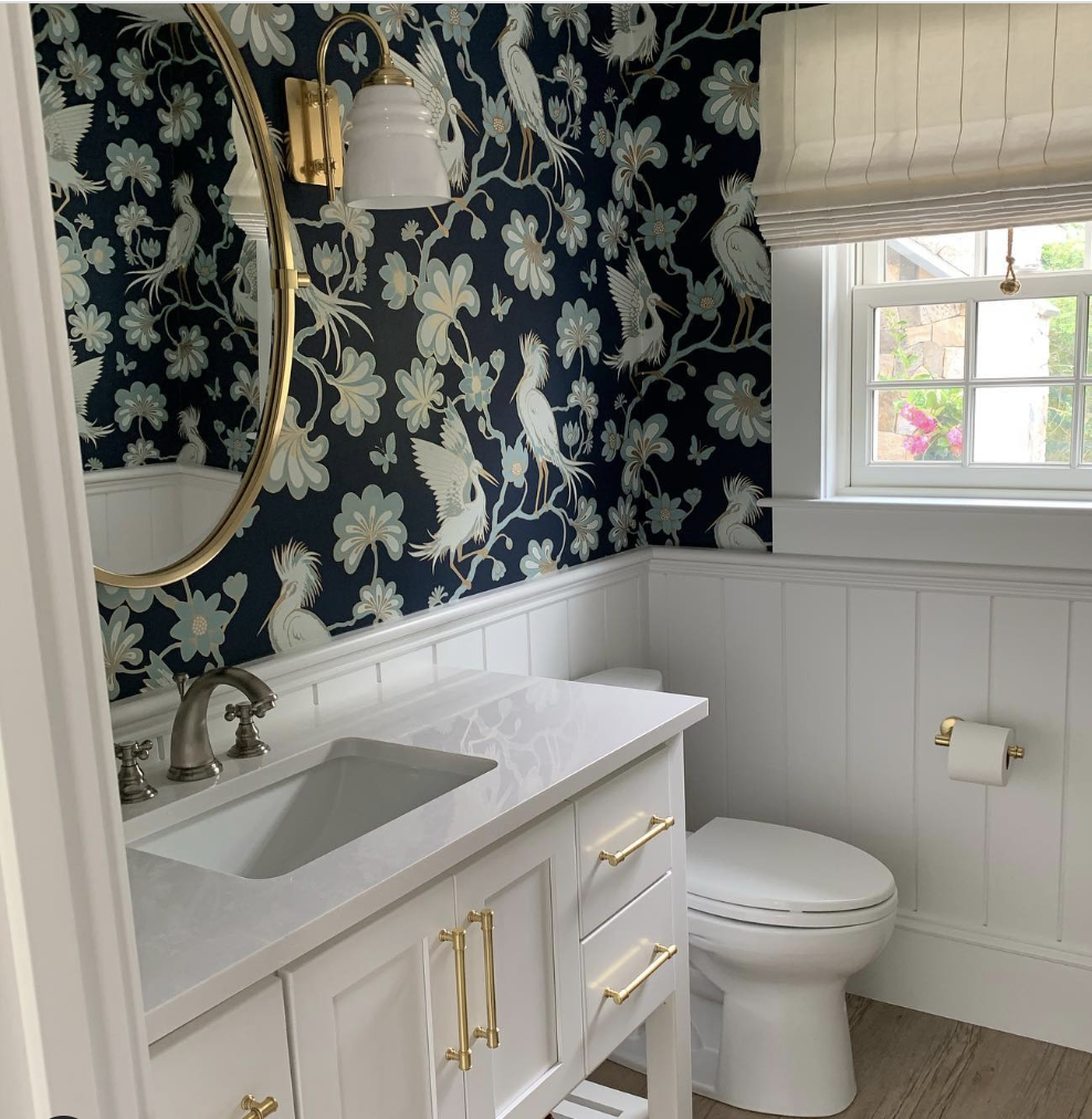 Bathroom with bold bird patterened wallpaper and white vanity