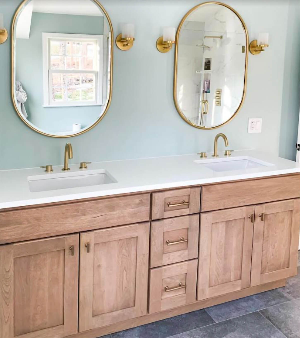 A trend-setting bathroom design with light stained oak cabinetry and brushed gold fixtures and hardware.