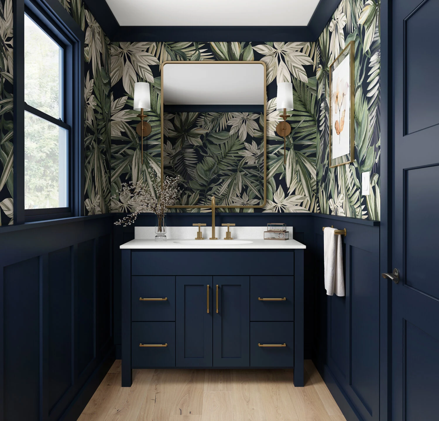 A trendy navy blue bathroom with a furniture style blue vanity with a solid white countertop, gold/brushed brass hardware, blue wainscot panels, and a fashionable blue, green, and white wallpaper.