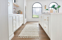 A bright, all-white kitchen with an elegant flat panel cabinet door style and a long kitchen island.
