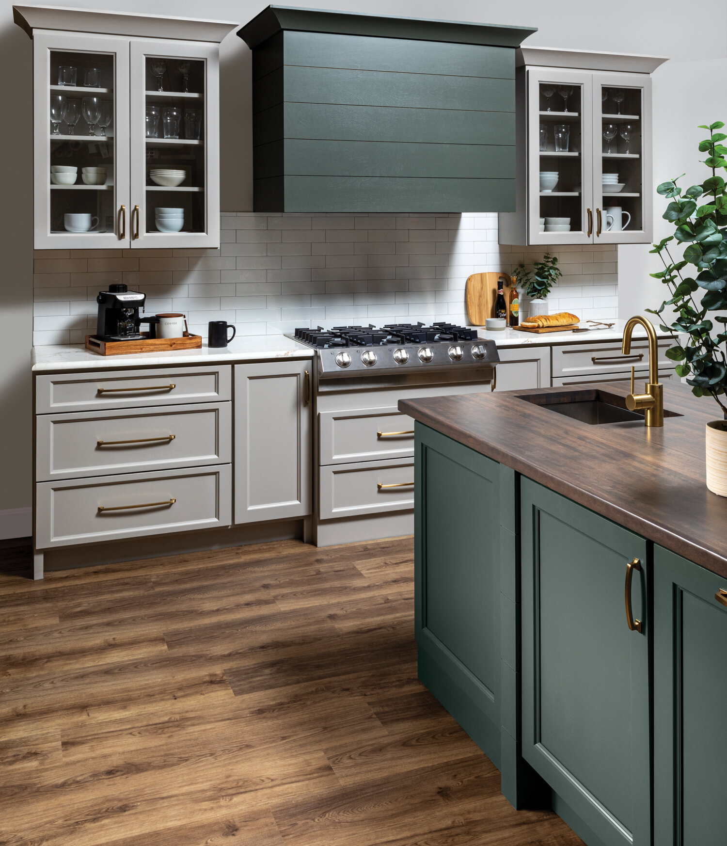 A kitchen with a modern wood hood with shiplap details and a hunter green painted finish surrounded by off-white, light gray cabinets with a dramatic flat panel door style.