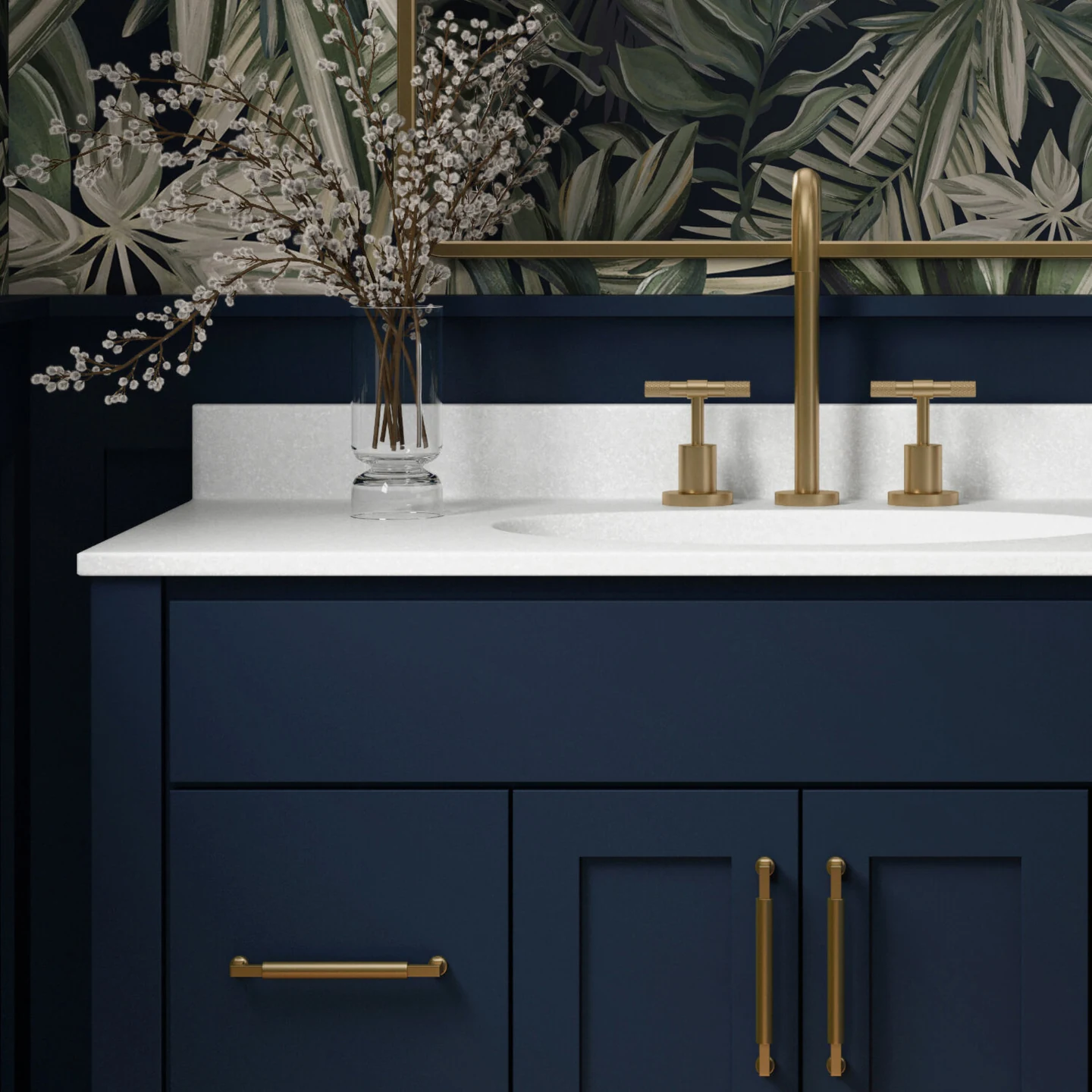 A trendy navy blue bathroom with a furniture style blue vanity with a solid white countertop, gold/brushed brass hardware, blue wainscot panels, and a fashionable blue, green, and white wallpaper.