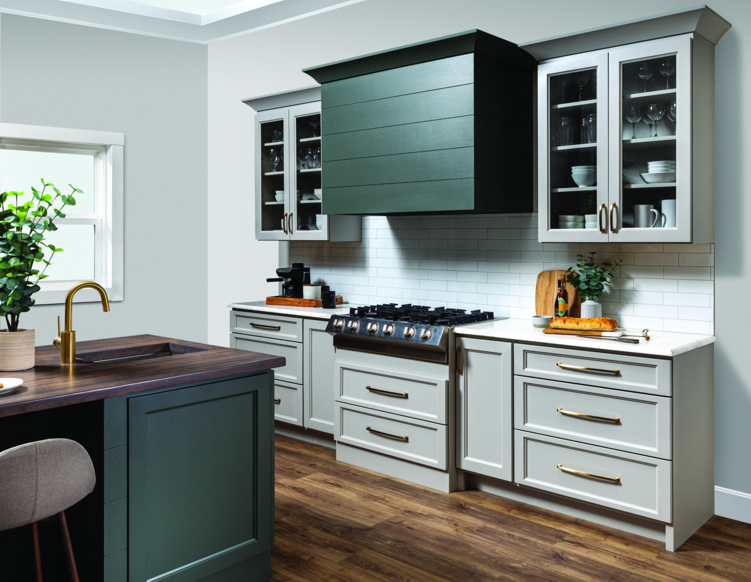 A kitchen with a modern wood hood with shiplap details and a hunter green painted finish surrounded by off-white, light gray cabinets with a dramatic flat panel door style.