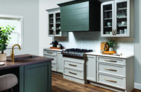 A kitchen with a modern wood hood with shiplap details and a hunter green painted finish surrounded by off-white, light gray cabinets with a dramatic flat panel door style.
