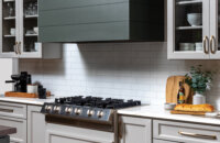 A close up of a modern wood hood with shiplap details and a hunter green painted finish.