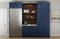 A close up of navy blue glossy acrylic cabinets with a contemporary slab cabinet door style with a contrasting beverage center in a rich, warm stained wood finish with matching floating shelves.