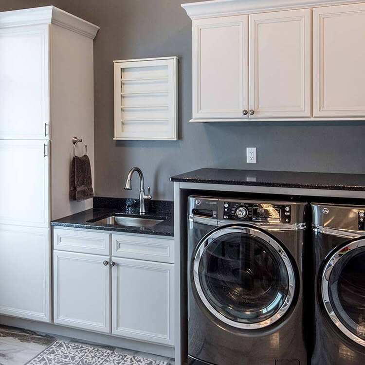An organized laundry room with Bertch cabinets in a white painted finish.