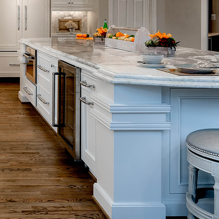 A large kitchen island featuring grand sized column details and decorative molding in an all-white kitchen design.