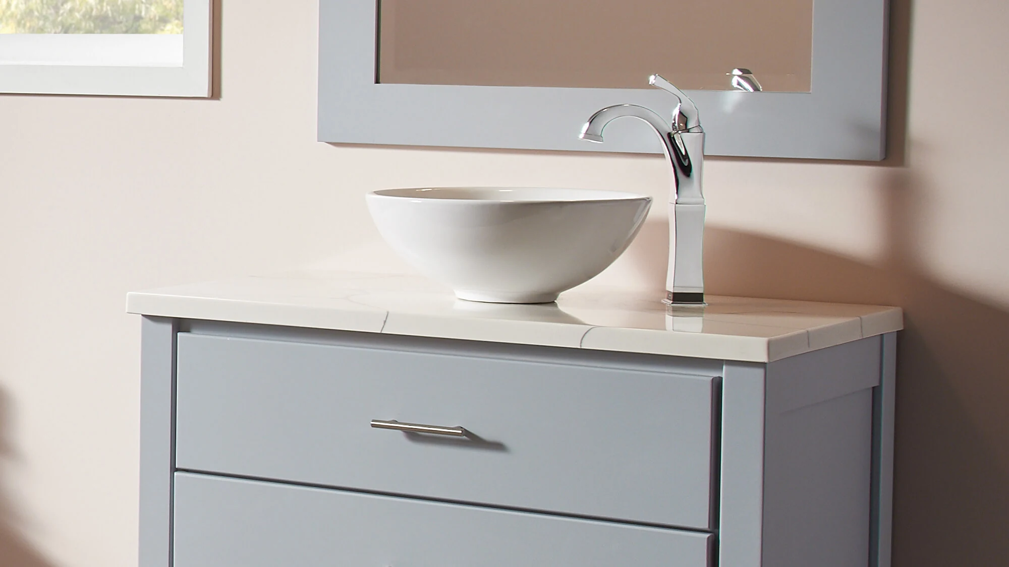 A vessel sink and vanity top combo on a modern gray painted vanity with a coordinating mirror.