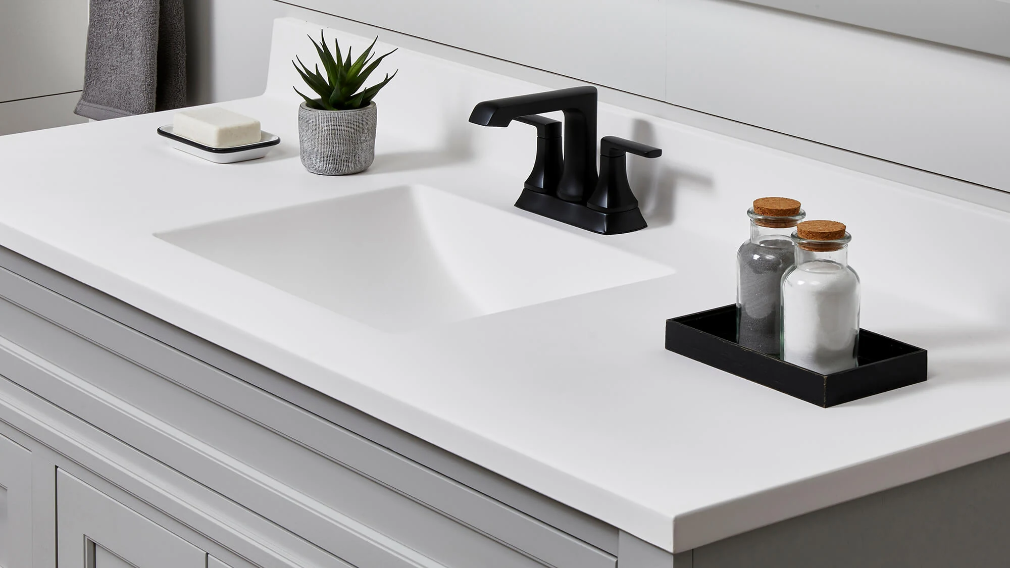 An Integral sink vanity top with a solid white surface on a gray painted vanity with black hardware.