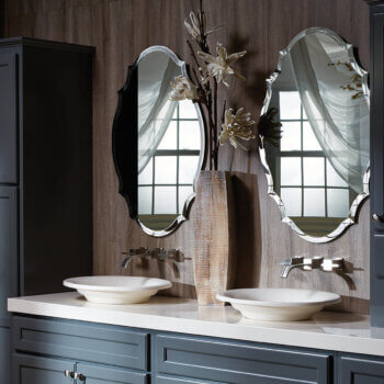 A double sink vanity with two elegant, Medallion shaped mirrors with a beveled detail along the outer edges.