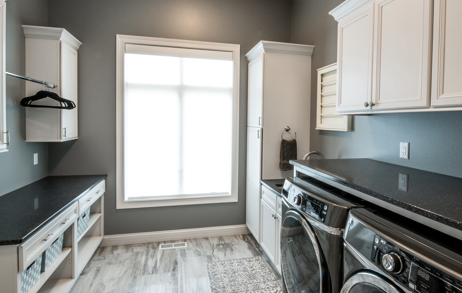 A beautiful and organized laundry room with bright white painted shaker cabinets from Bertch.