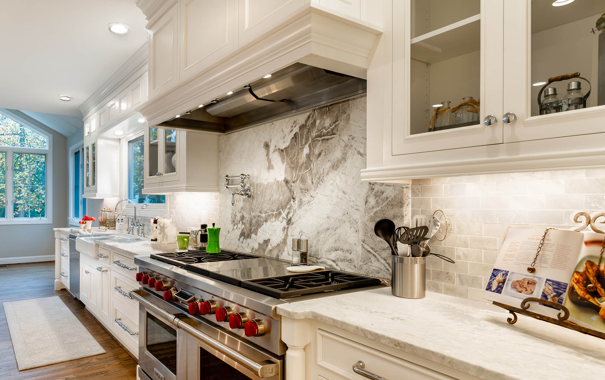 An all white kitchen design with soft, white painted cabinets and a wood hood from Bertch Cabinet.